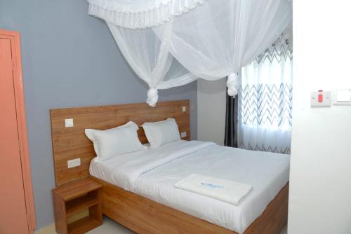 a bedroom with a bed with white sheets and a window at Hotel Bustani in Naivasha