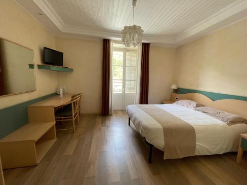 a bedroom with a bed and a desk and a television at Le Mirval in La Brigue