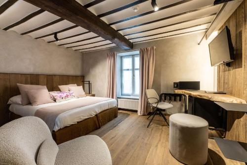 a bedroom with two beds and a tv and chairs at Hotel LEA - Maison Caerdinael in Durbuy