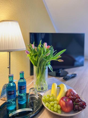 a table with a plate of fruit and a vase of flowers at Pension Schlossblick in Sondershausen