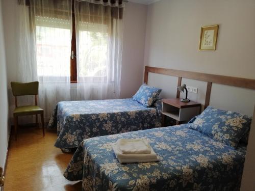 a room with two beds and a chair and a window at Casa La Granda in Cangas de Onís