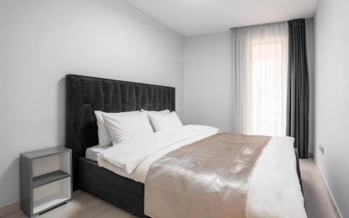 Avand Apartments Debrecen في ديبريتْسين: غرفة نوم مع سرير كبير مع اللوح الأمامي الأسود