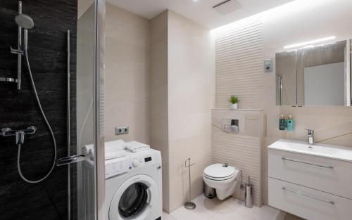 a bathroom with a washing machine and a sink at Avand Apartments Debrecen in Debrecen