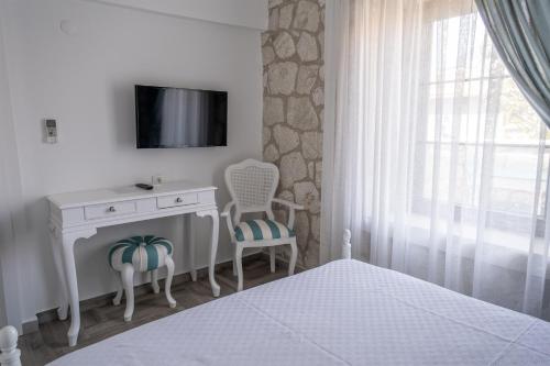 a bedroom with a bed and a desk and a tv at TaşAda Hotel - Special Class in Bozcaada