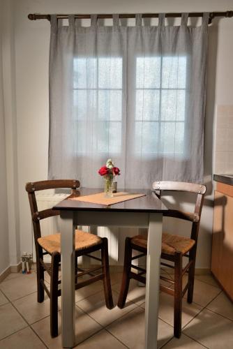 a dining room table with two chairs and a window at Artemis Apartments in Konitsa