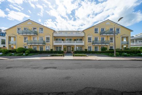 a large yellow building with balconies on a street at Arkona Strandresidenzen in Binz