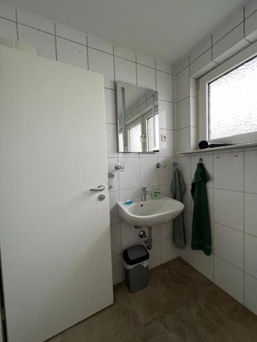 a white bathroom with a sink and a mirror at Ferienhaus-Ost in Gießen