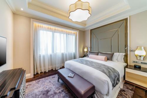 a bedroom with a large bed and a large window at Caravelle Saigon in Ho Chi Minh City