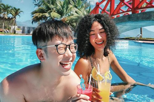 un hombre y una mujer en una piscina con bebidas en Da Nang - Mikazuki Japanese Resorts & Spa en Da Nang
