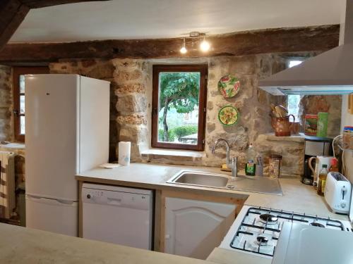 une cuisine avec un réfrigérateur blanc et un évier dans l'établissement Proche baignade, La Bergerie de Claire, à Thoiras