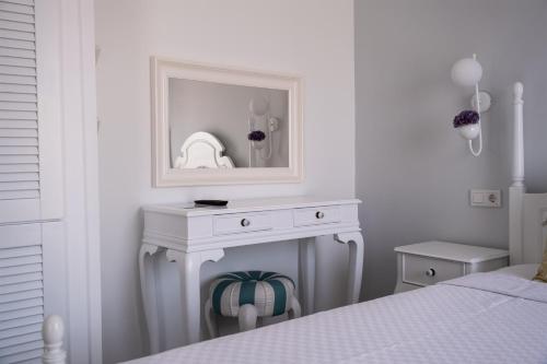 a white bedroom with a white dressing table and a mirror at TaşAda Bozcaada in Bozcaada