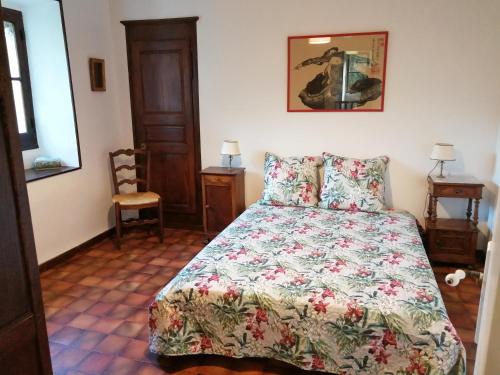 une chambre avec un lit avec un couvre-lit fleuri dans l'établissement Proche baignade, La Bergerie de Claire, à Thoiras