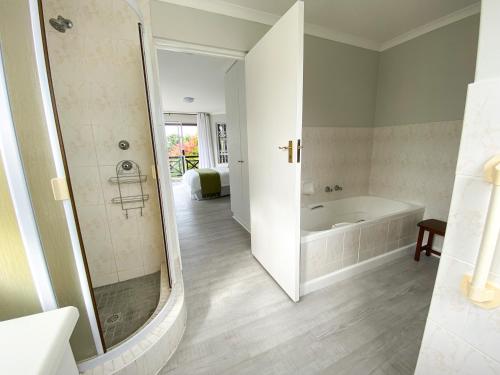 uma casa de banho branca com uma banheira e um chuveiro em 34 Summerplace em Knysna