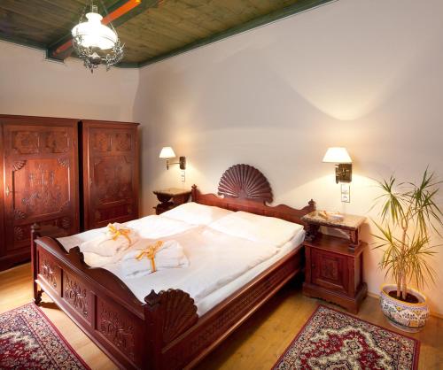 Un dormitorio con una cama grande con sábanas blancas y muebles de madera. en Jurkovičův dům, en Luhačovice