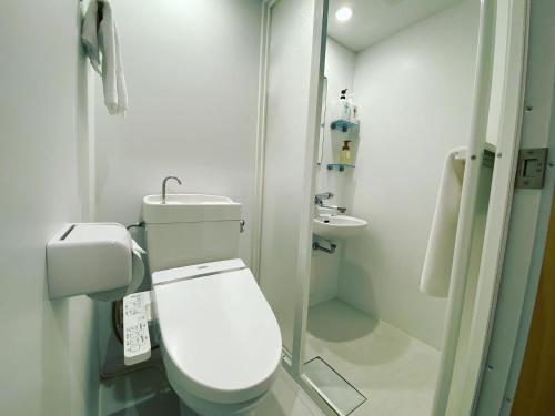 a white bathroom with a toilet and a sink at HafH Fukuoka THE LIFE in Fukuoka