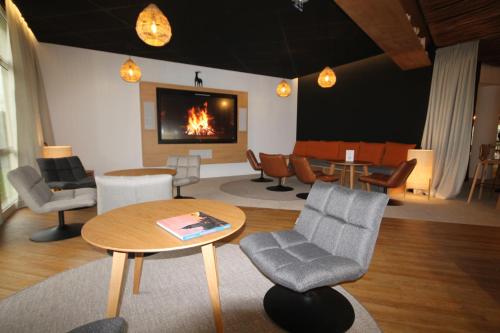 a living room with chairs and a table and a fireplace at Mercure Compiègne Sud in Compiègne