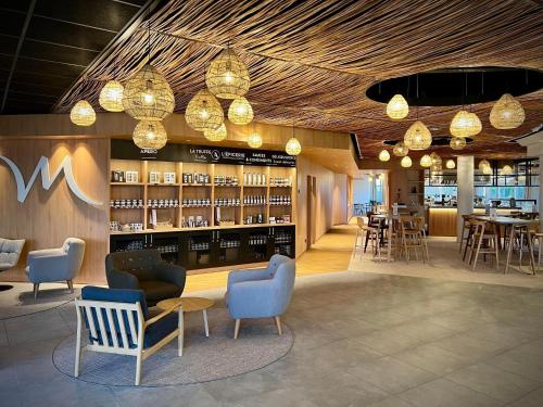a restaurant with chairs and tables and chandeliers at Mercure Compiègne Sud in Compiègne