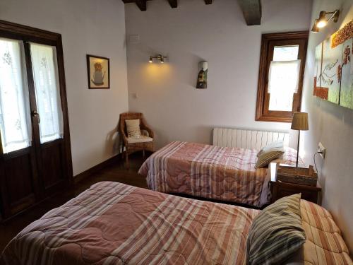 a bedroom with two beds and a chair and windows at Alberroakoborda in Ituren