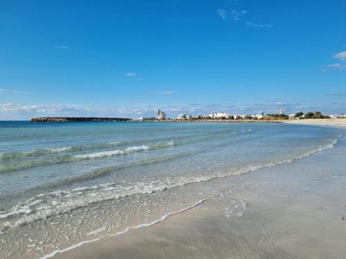 a beach with the ocean and buildings in the background at Fronte Mare in Torre San Giovanni Ugento