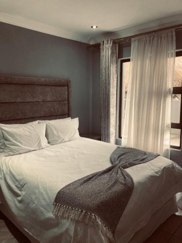 a bedroom with a large white bed with a window at President Guest Lodge in Louis Trichardt