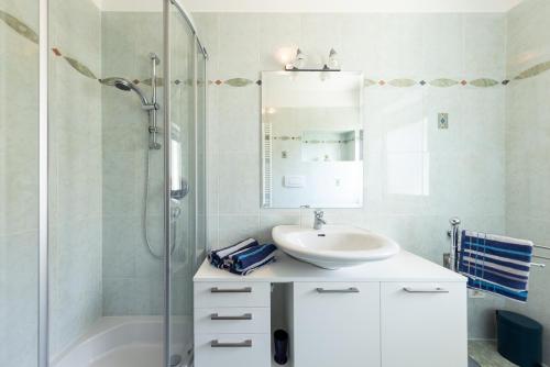 a white bathroom with a sink and a shower at Haus Dorfblick in Caldaro
