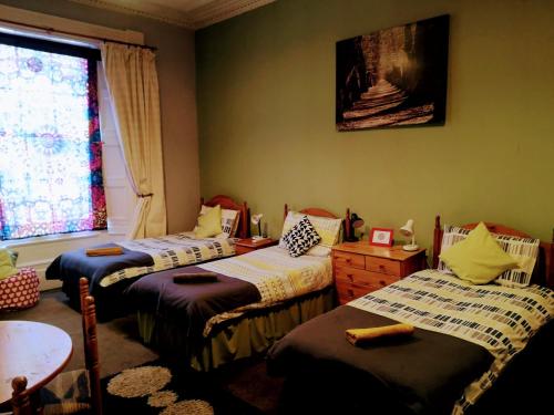 a room with three beds and a window at aabAlree Guest House in Dundee