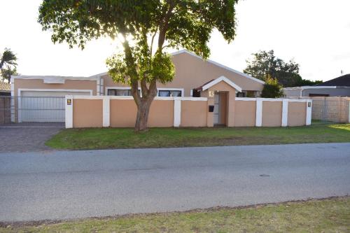 a house with a tree in front of a driveway at Zufike Self Catering in Port Elizabeth