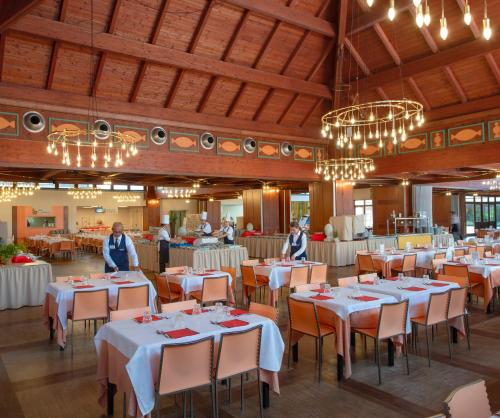 una sala da pranzo con tavoli e sedie bianchi e lampadari a braccio di Ethra Reserve Valentino a Castellaneta Marina