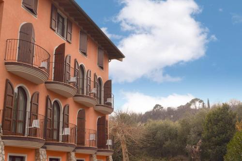 ein großes orangefarbenes Gebäude mit Balkon an der Seite in der Unterkunft AHG Donna Silvia Wellness Hotel in Manerba del Garda