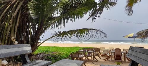 a table and chairs on a beach with the ocean at Sea Garden Beach Resort in Habaraduwa