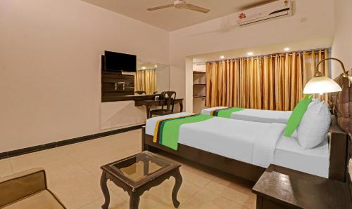 a bedroom with a bed and a table and a desk at Treebo White Inn Koramangala in Bengaluru