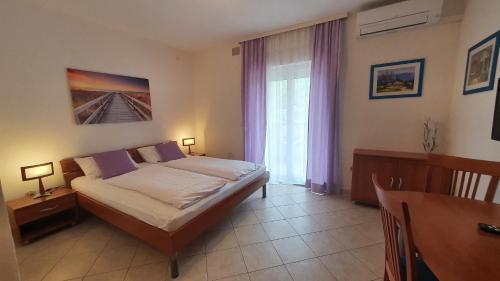 een slaapkamer met een bed, een tafel en een raam bij B&B Villa La Perla in Punat