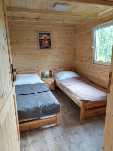 two beds in a log cabin with a window at Na polance dwa domki in Chłopy