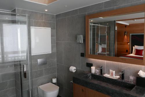 a bathroom with a sink and a toilet and a mirror at Hôtel Alparena & Spa - 4 étoiles in La Rosière