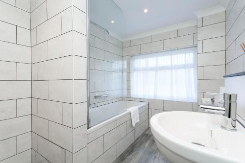 ein weißes Badezimmer mit einer Badewanne und einem Waschbecken in der Unterkunft Deans Place Hotel in Alfriston