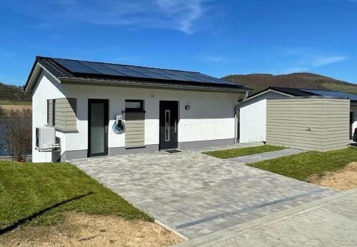 una casa blanca con techo solar encima en Ferienhaus Diemelblick en Heringhausen