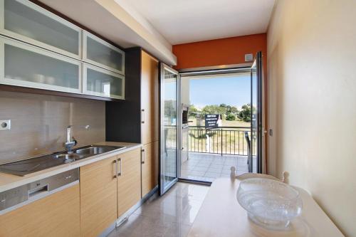 a kitchen with a sink and a door to a balcony at Varandas do Sol - Olhos de Água in Albufeira