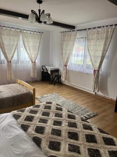 sypialnia z łóżkiem, stołem i oknami w obiekcie Casa Firuta Borsa w mieście Borşa