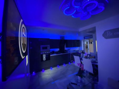 a kitchen with blue lighting and a person sitting on a couch at NEW…THE HOTTUB HOUSE BLACKPOOL PLEASURE BEACH in Blackpool