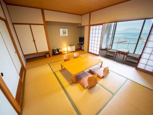 a living room with a table and chairs and a balcony at Kokumin Shukusha Marine Terrace Ashiya in Kitakyushu