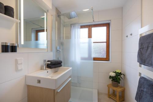 a white bathroom with a sink and a mirror at Ferienwohnungen Alpentraum - Alpensonne in Oberstdorf