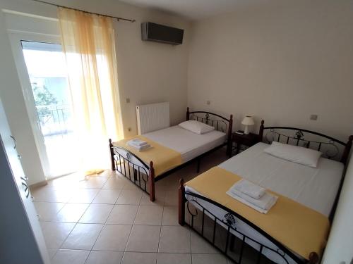 - 2 lits dans une chambre avec une grande fenêtre dans l'établissement Philoxenia Apartments II, à Plataria