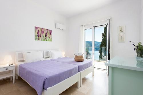 une chambre blanche avec un lit et une table en verre dans l'établissement Thalia's House, à Paleokastritsa