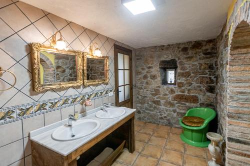 a bathroom with two sinks and a green trash can at Floreu de Remis casa in Soto de Cangas