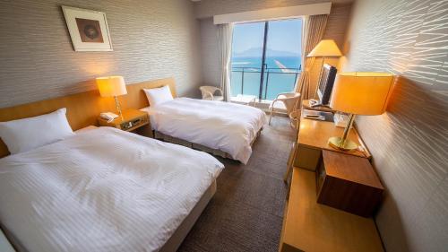 a hotel room with two beds and a window at Kokumin Shukusha Marine Terrace Ashiya in Kitakyushu