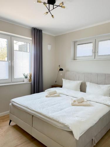 a bedroom with a large white bed with two towels on it at Ferienwohnung The Hideaway in Scharbeutz