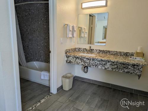 a bathroom with a sink and a tub and a mirror at Royal Inn in South San Francisco
