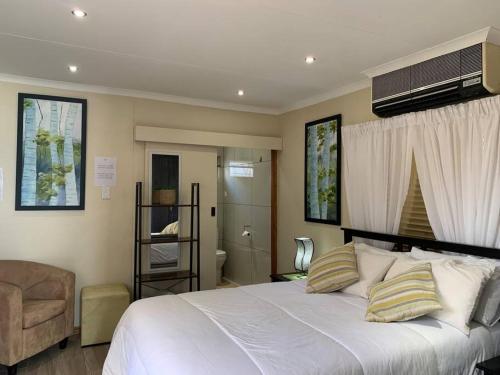 a bedroom with a large white bed and a bathroom at Orange Breeze Self-Catering Apartment in Kakamas