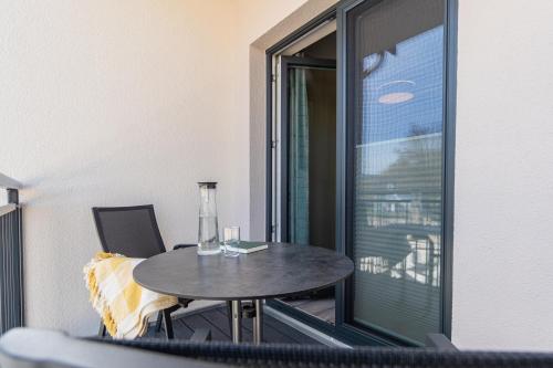 a small table and chairs on a balcony with a window at Ostsee Apartmenthotel in Graal-Müritz