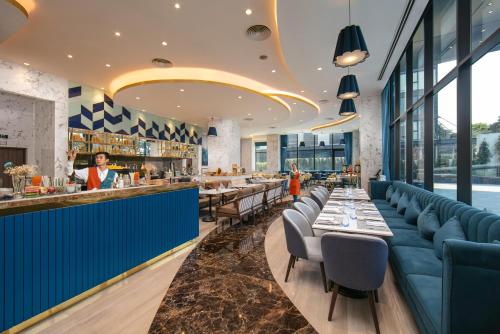 a restaurant with blue seating and a bar with tables at Mövenpick Living West Hanoi in Hanoi